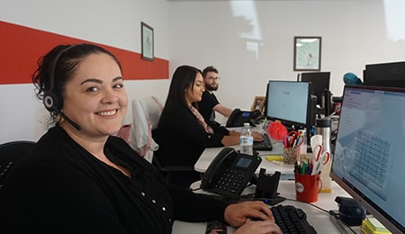 Three customer support staff working on a computer.